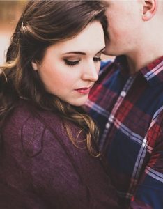 A young woman in beautiful natural makeup poses with her significant other for a photo of the couple.